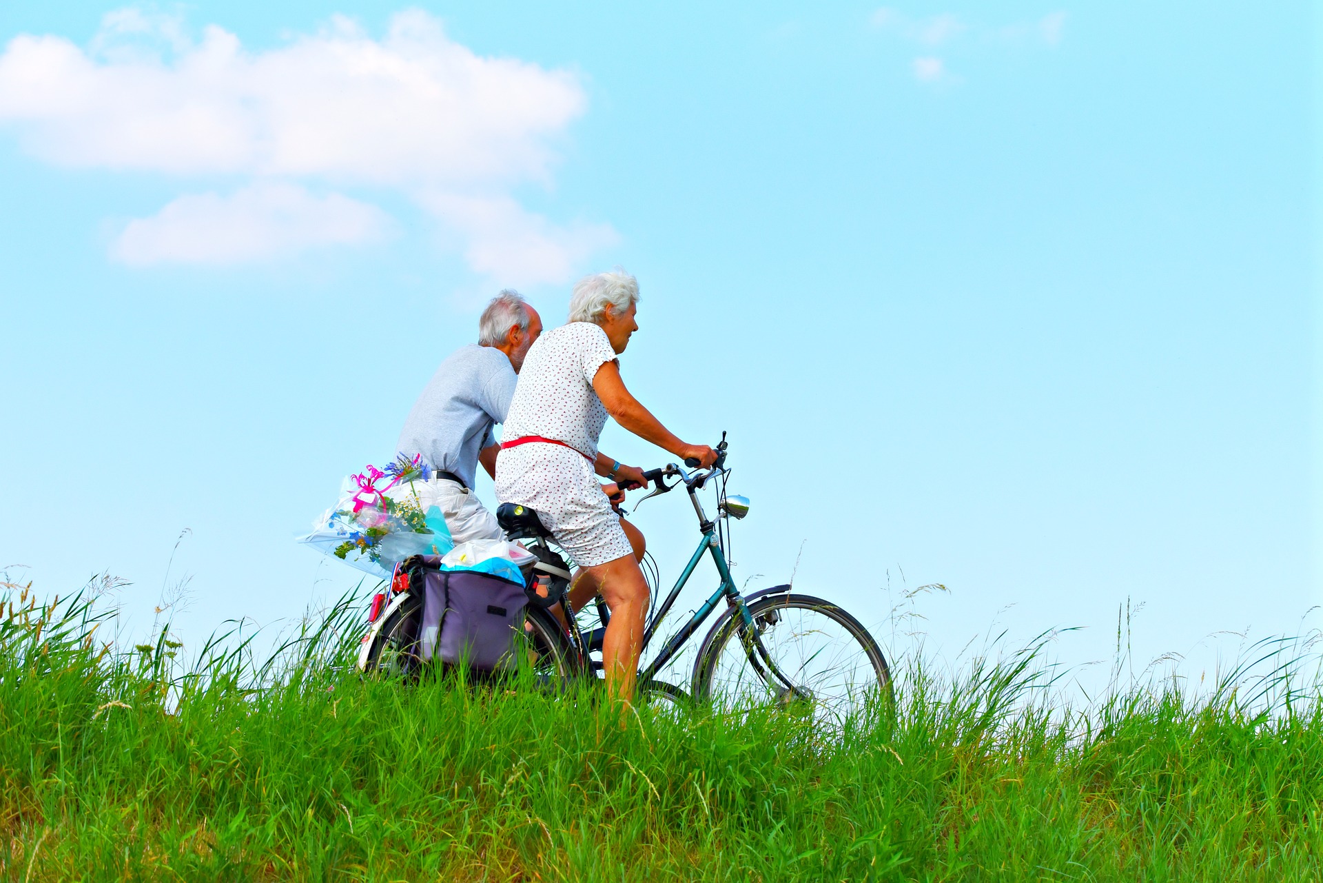 Elderly couple riding bikes in grass
